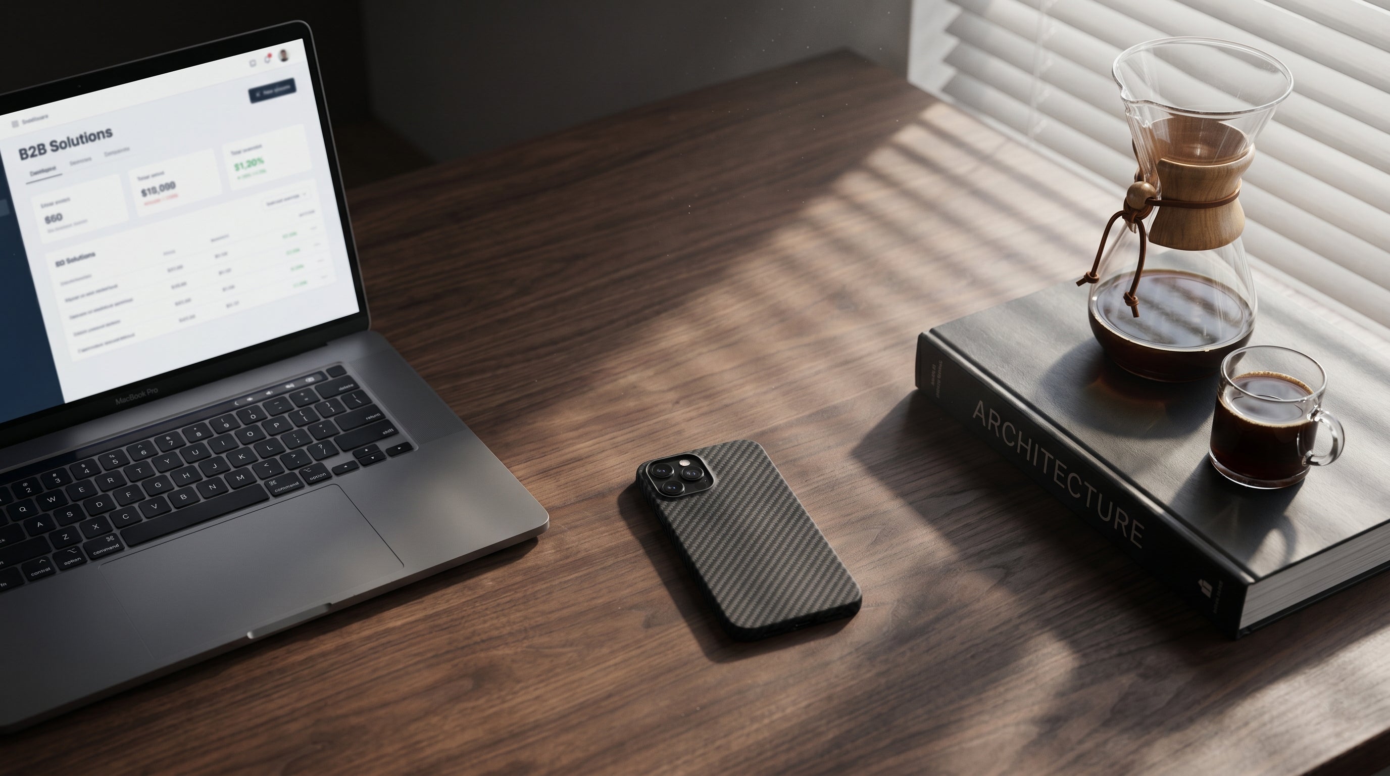 CHICDEX high-end phone case and a laptop showing B2B wholesale dashboard on a walnut desk.